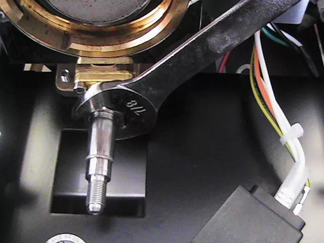 A close-up of a 7/8 inch wrench on a metal bolt during an OPV adjustment, with wires and mechanical parts from a Rancilio Silvia espresso machine visible in the background. © 2025 1st-line.com