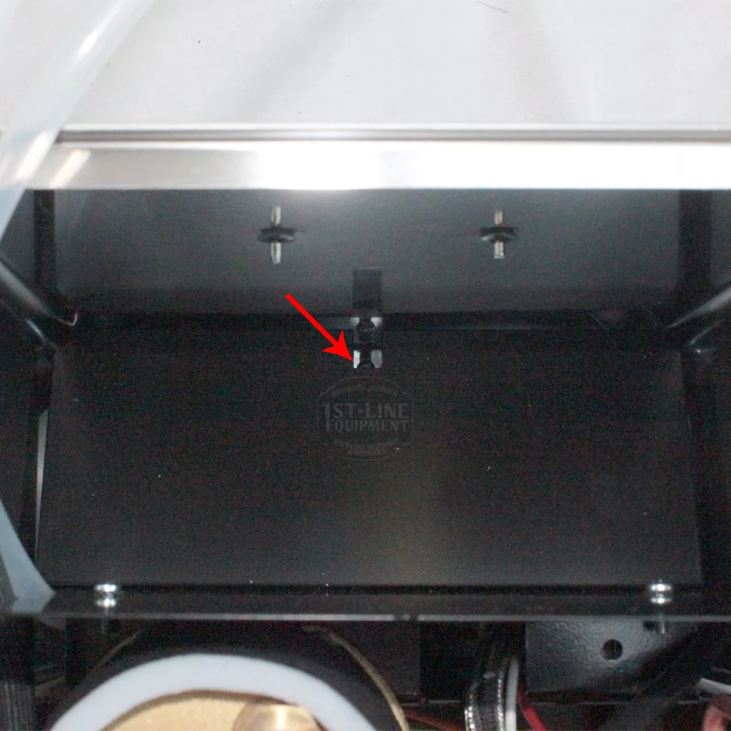 A close-up of a black metal surface inside a machine, possibly the Rancilio Silvia, with a red arrow pointing to a small black sensor under a horizontal bar. The faint 1st-Line Equipment logo is visible. © 2025 1st-line.com
