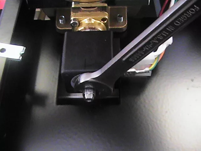 A wrench is tightening a nut on a black component of a Rancilio Silvia espresso machine, with wires connected nearby and a brass fitting mounted above, all on a dark surface, likely during an OPV adjustment. © 2025 1st-line.com