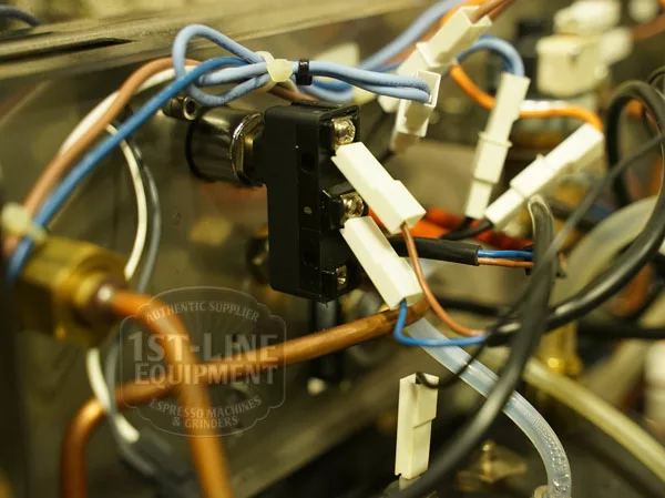 Close-up of electrical wiring, connectors, and metal pipes inside the Elektra Verve Dual Boiler Espresso Machine, highlighting its internal components and the 1st-Line Equipment logo on the glass. © 2025 1st-line.com