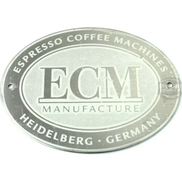 The ECM ER8285 Rear Panel Logo is an oval silver metal plate featuring embossed text—ESPRESSO COFFEE MACHINES, ECM MANUFACTURE, and HEIDELBERG GERMANY—surrounding the ECM logo in the center; typically used on the ER8285. © 2025 1st-line.com