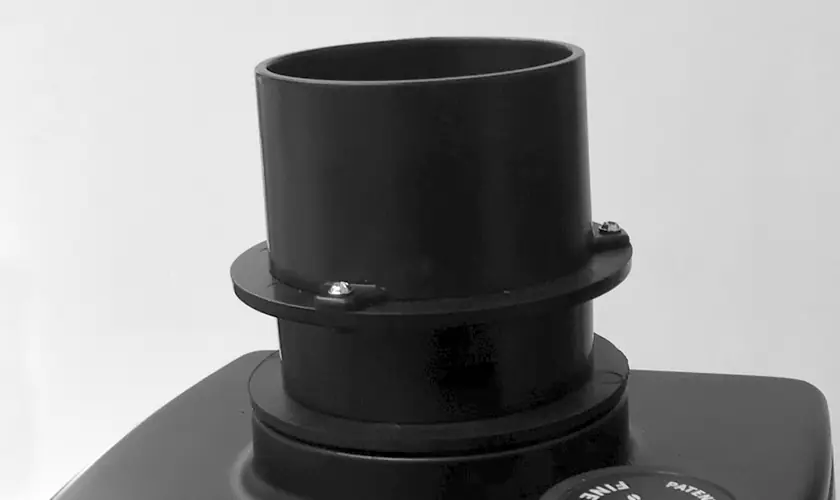 A close-up of a cylindrical black plastic pipe fitting with screws, mounted on a flat black surface against a plain background&mdash;resembling components in the Eureka Atom W 75 Weight Based Espresso Coffee Grinder. &copy; 2025 1st-line.com