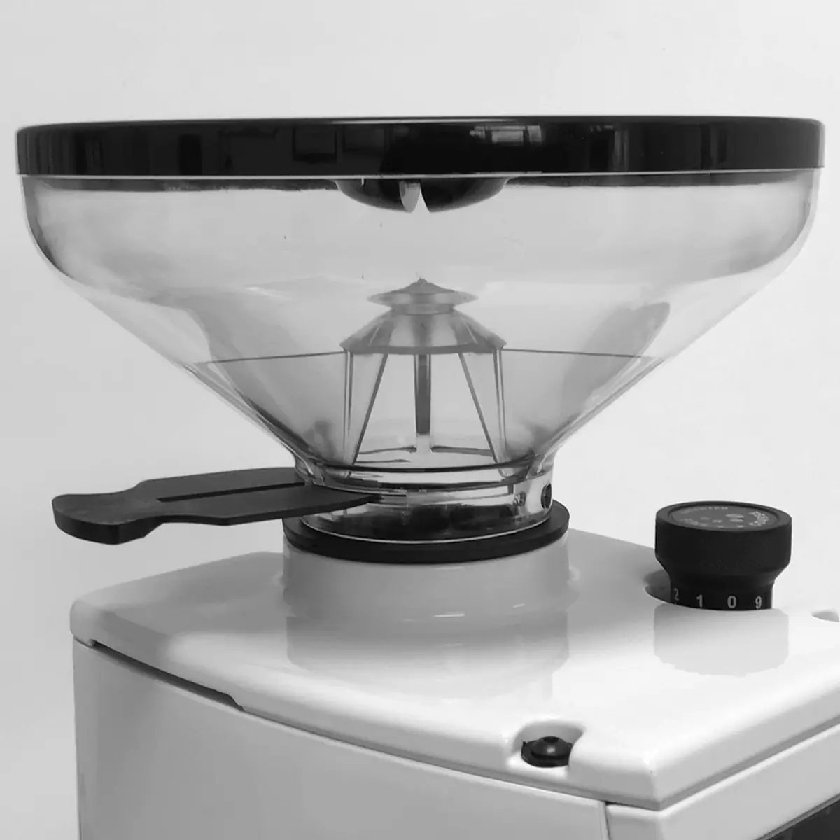 A close-up of the Eureka Atom W 65 Weight Based Espresso Coffee Grinder shows its transparent hopper, numbered right-side dial, and black left-side lever for precise espresso grinding. © 2025 1st-line.com